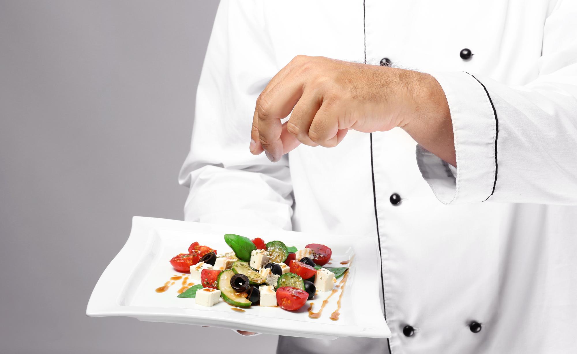 Chef demonstrating plating technique in bright kitchen